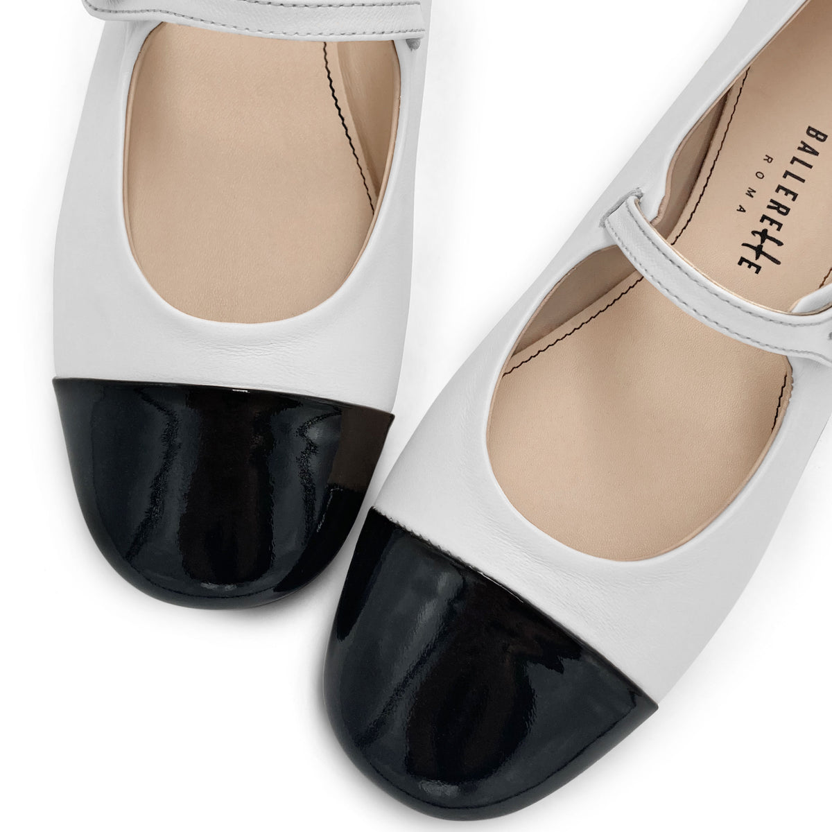White ballet flats with black patent toe and strap