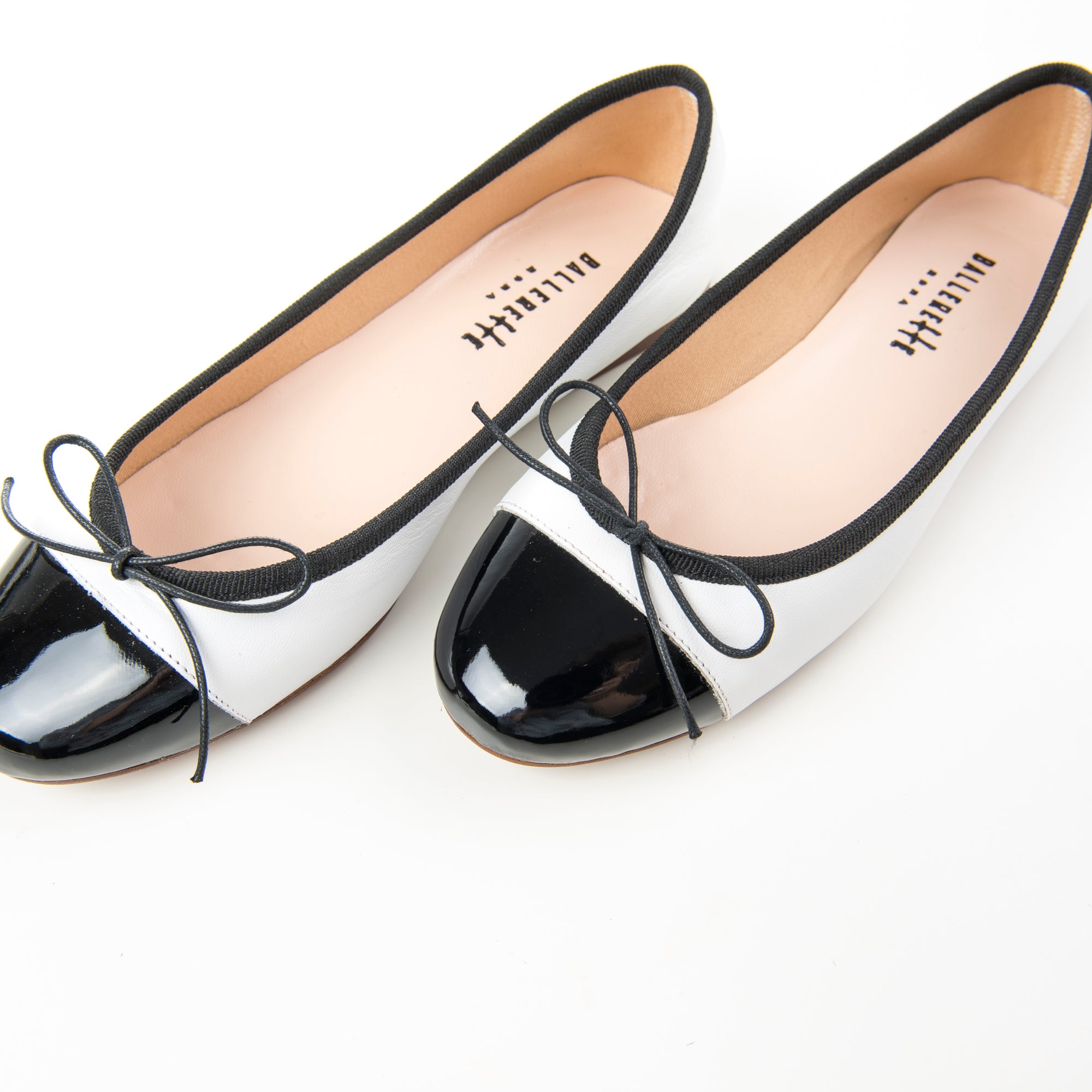 White leather ballet flats with black patent toe