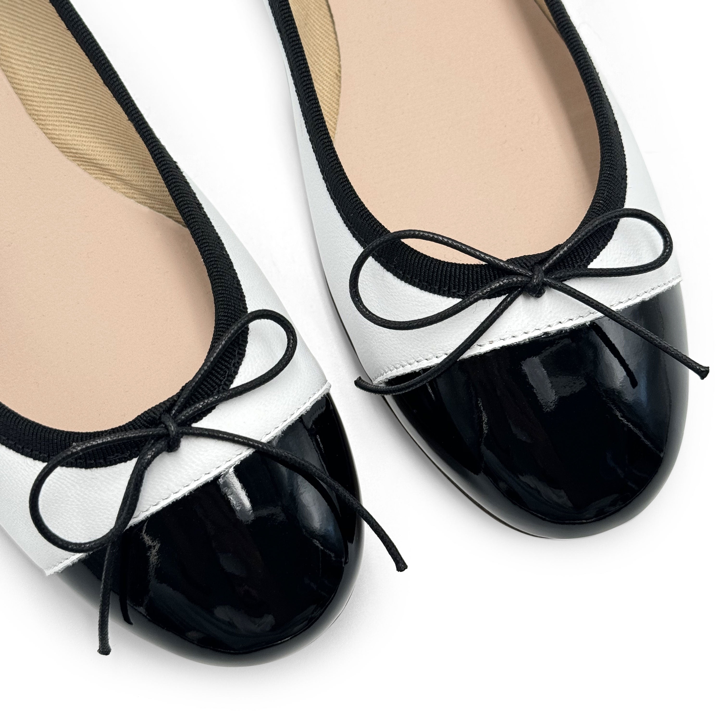 White leather ballet flats with black patent toe