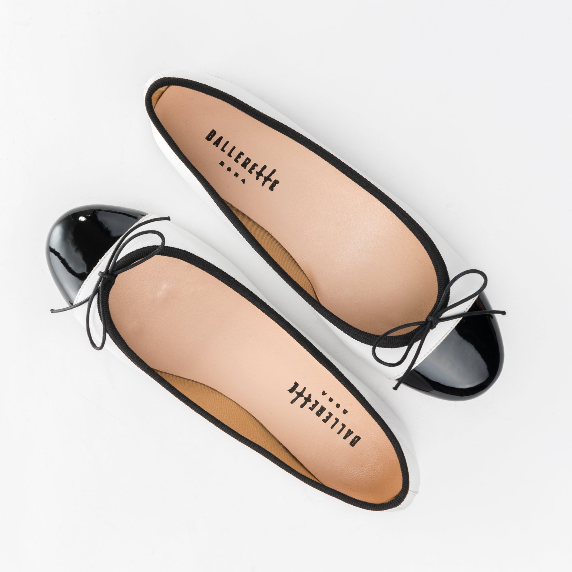 White leather ballet flats with black patent toe