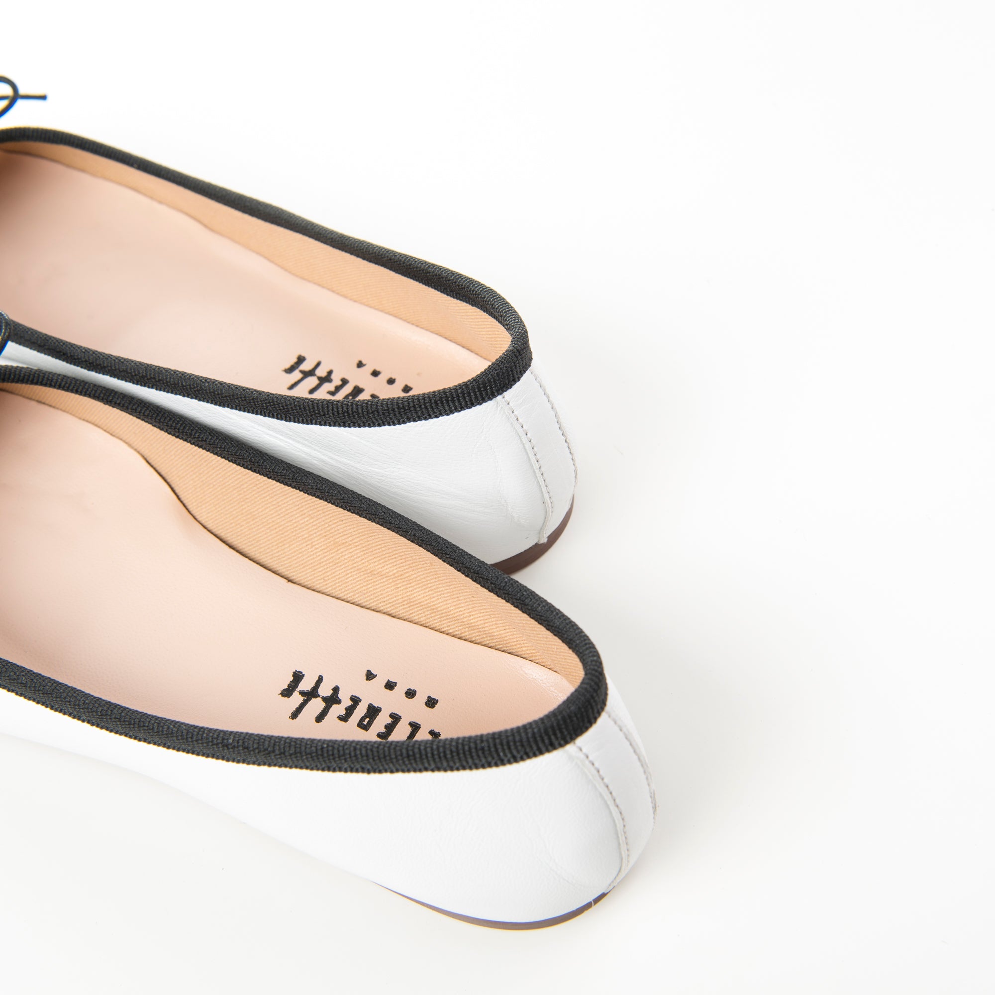 White leather ballet flats with black patent toe