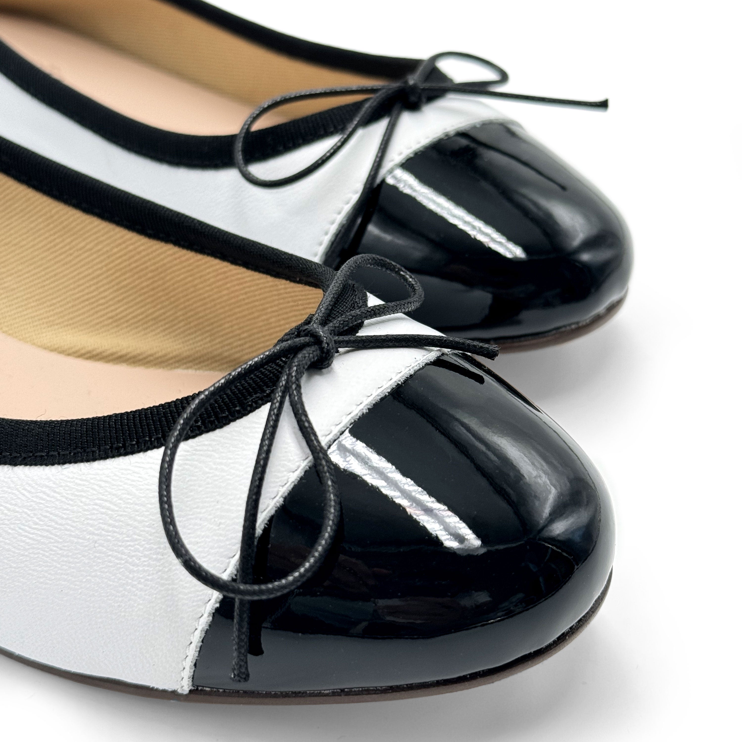 White leather ballet flats with black patent toe