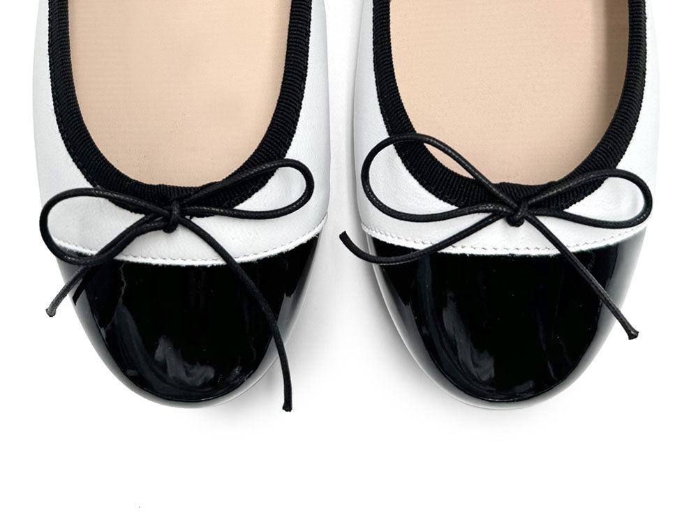 White leather ballet flats with black patent toe